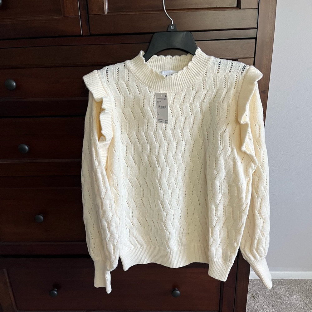FRNCH brand cream sweater with ruffled shoulder.